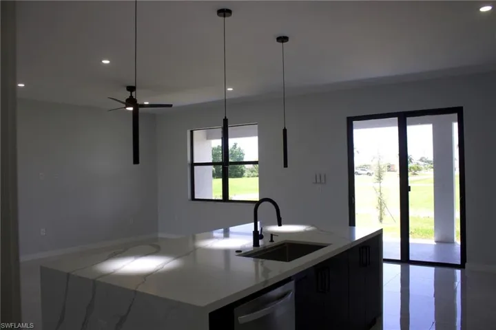 Kitchen featuring light stone countertops, an island with sink, stainless steel dishwasher, modern cabinets, and dark cabinets