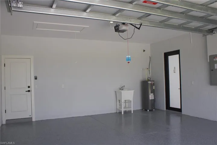 Garage with water heater, electric panel, and a garage door opener