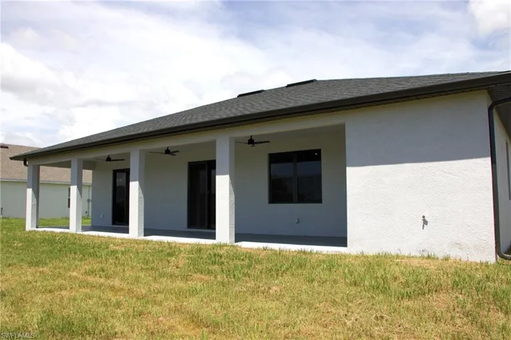 Back of property with a yard, stucco siding, ceiling fan, a patio, and a shingled roof