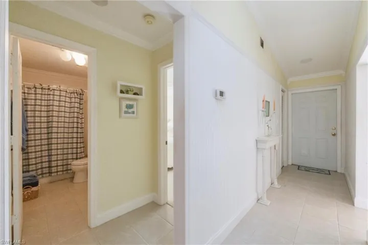 Hallway with ornamental molding and light tile patterned floors