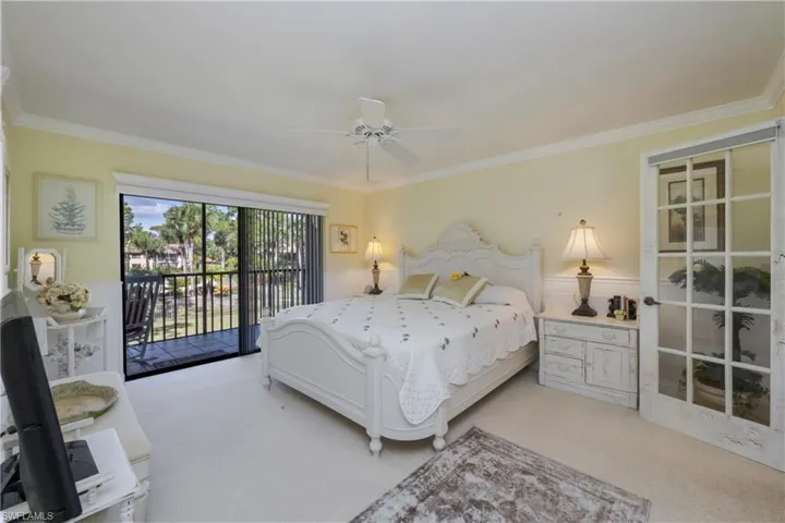 Bedroom with access to outside, light carpet, ornamental molding, ceiling fan, and wainscoting