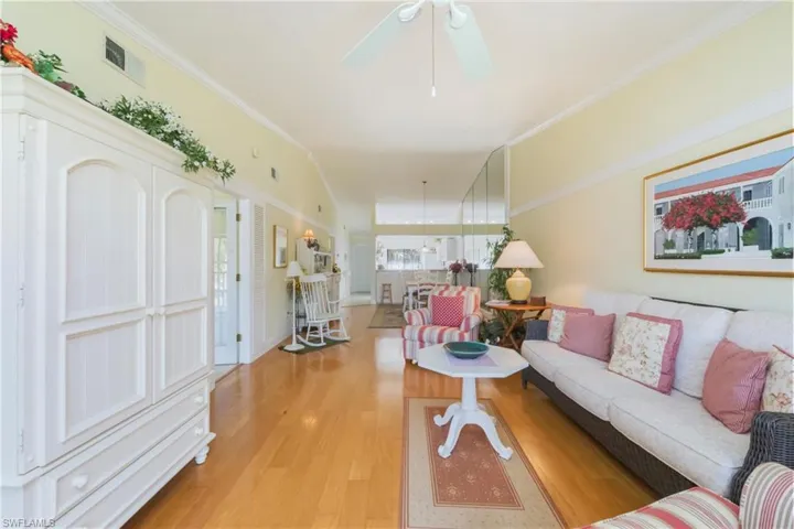 Living area featuring crown molding, wood finished floors, and a ceiling fan