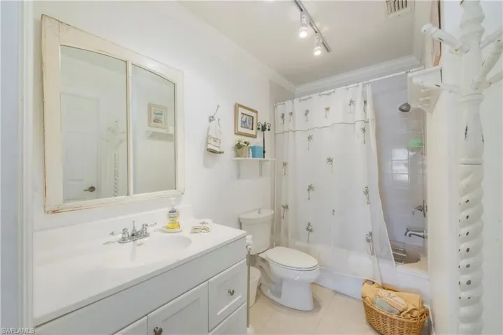Full bath with shower / tub combo, vanity, light tile patterned flooring, and ornamental molding