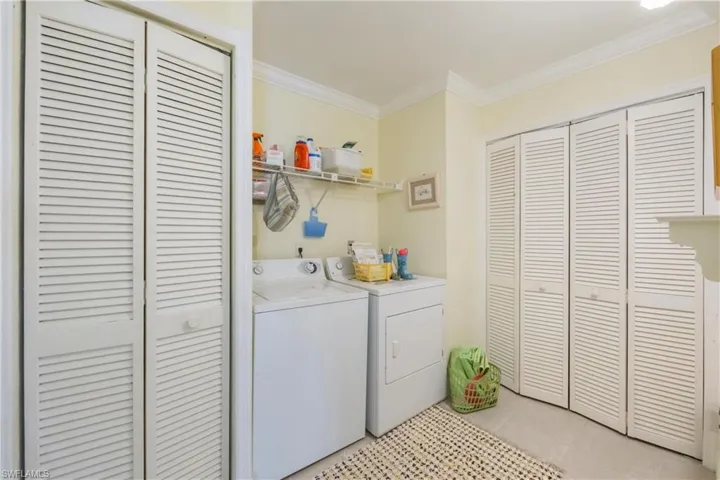 Laundry room featuring ornamental molding, light tile patterned floors, and washer and clothes dryer