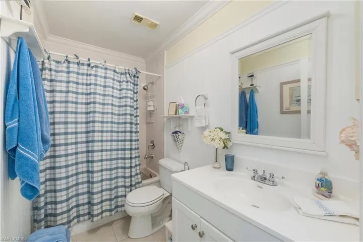 Full bath featuring shower / tub combo, vanity, crown molding, and light tile patterned floors