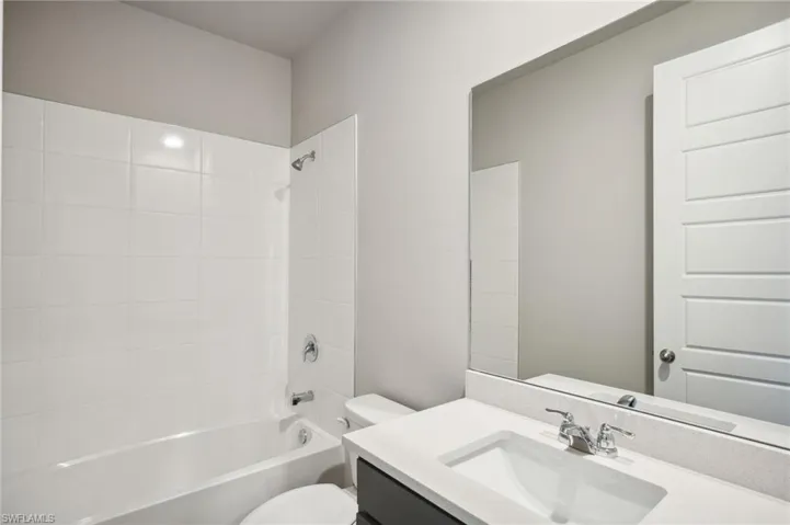 Full bathroom with vanity, tiled shower / bath, and toilet