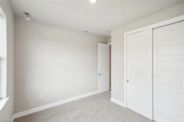 Unfurnished bedroom with light carpet and a closet