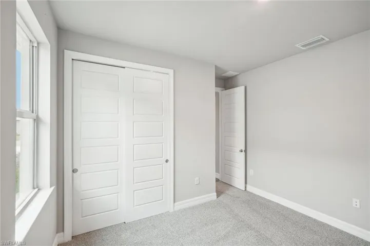 Unfurnished bedroom with a closet and light carpet
