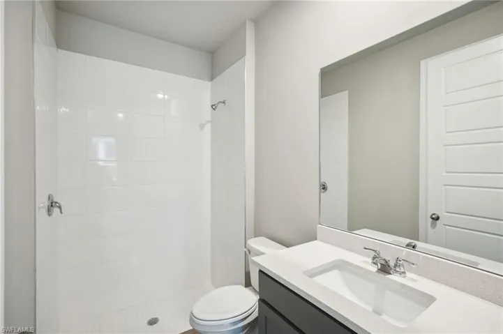 Bathroom featuring vanity, toilet, and a tile shower