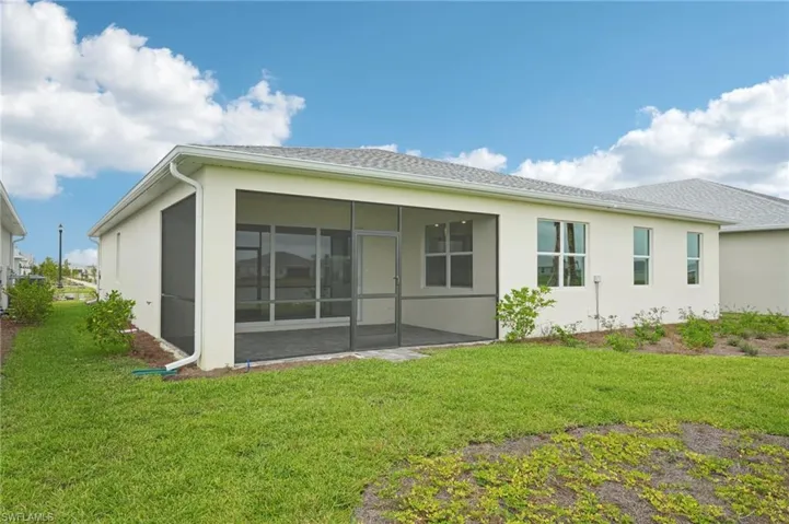 Rear view of property featuring a sunroom, a yard, and a patio area