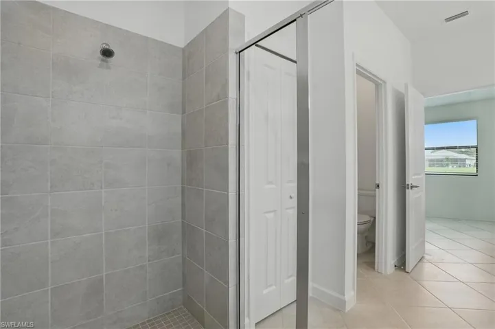 Full bath featuring a shower stall, toilet, and tile patterned floors