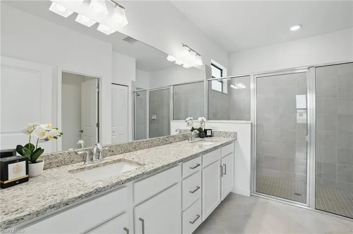 Full bathroom featuring double vanity, a shower stall, and tile patterned flooring