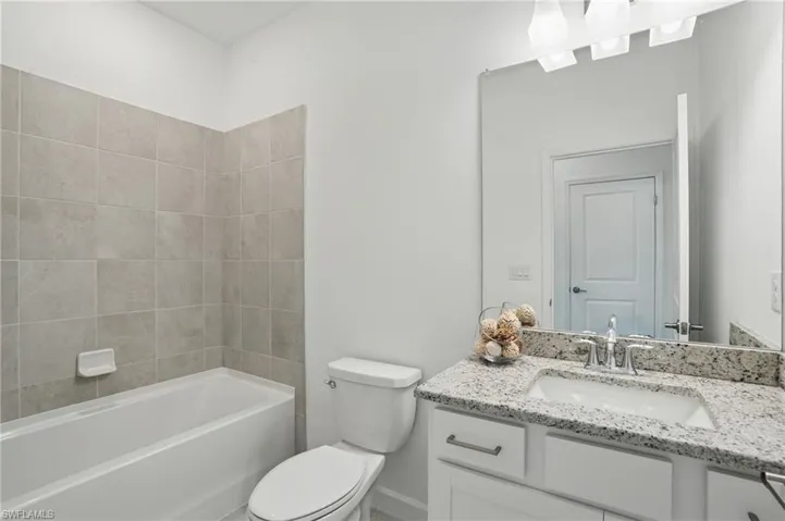 Bathroom with toilet, vanity, baseboards, and shower / bathtub combination