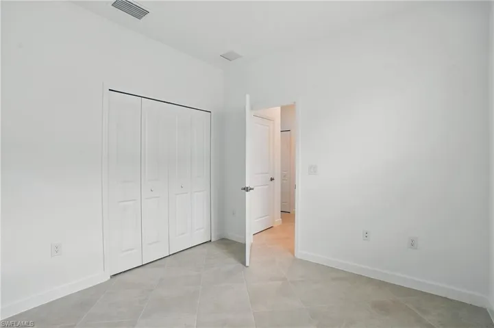 Unfurnished bedroom featuring light tile patterned flooring, baseboards, and a closet