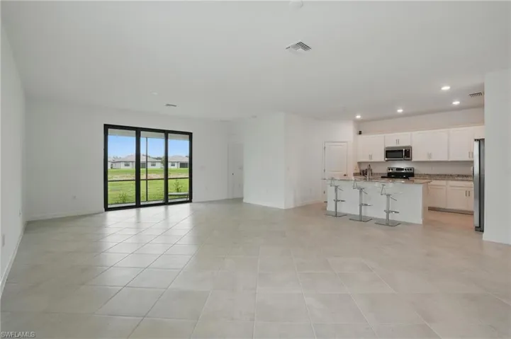 Unfurnished living room with recessed lighting, baseboards, light tile patterned floors, and a sink