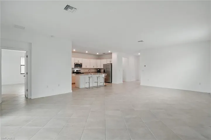 Unfurnished living room featuring recessed lighting, light tile patterned flooring, a sink, and baseboards