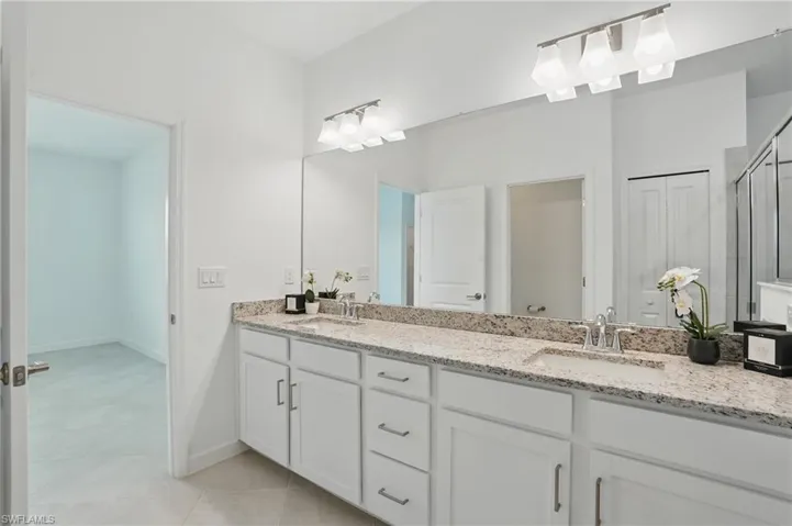 Bathroom with double vanity, tile patterned flooring, a shower with door, and baseboards