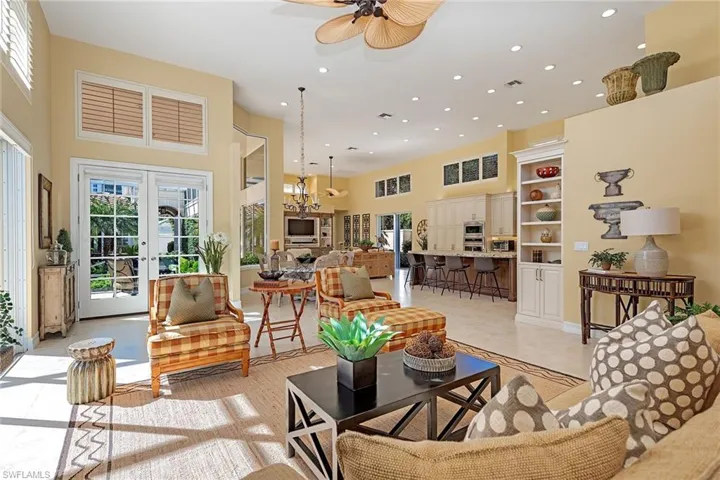Living area featuring plenty of natural light, recessed lighting, light tile patterned floors, a towering ceiling, and french doors