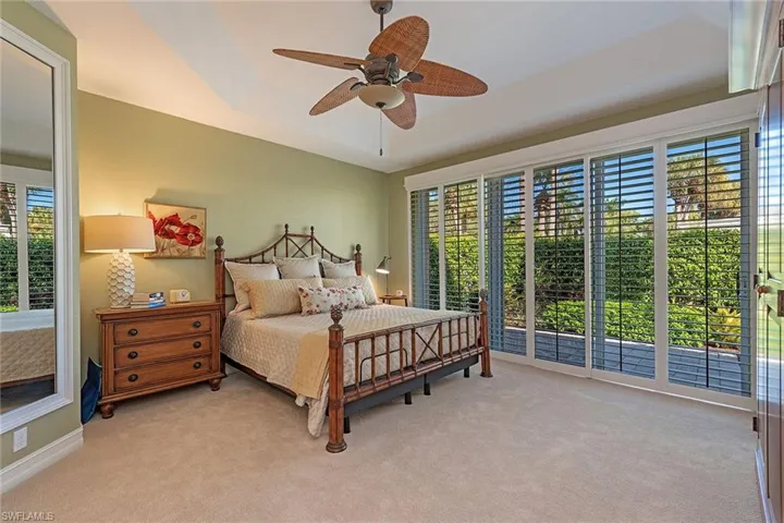 Bedroom with light colored carpet, access to exterior, ceiling fan, and a tray ceiling