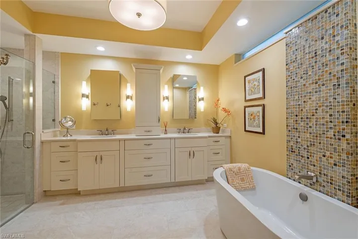 Full bathroom featuring double vanity, a soaking tub, a shower stall, recessed lighting, and light tile patterned floors