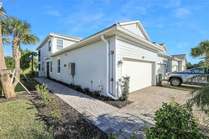 One story FIRST FLOOR residence featuring light-toned horizontal siding, a private paver driveway, an attached garage, and a paver walkway leading to the entrance