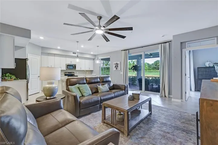 Open-concept interior featuring white cabinetry, a large-format multi-blade ceiling fan, recessed lighting, and hurricane impact sliding glass doors