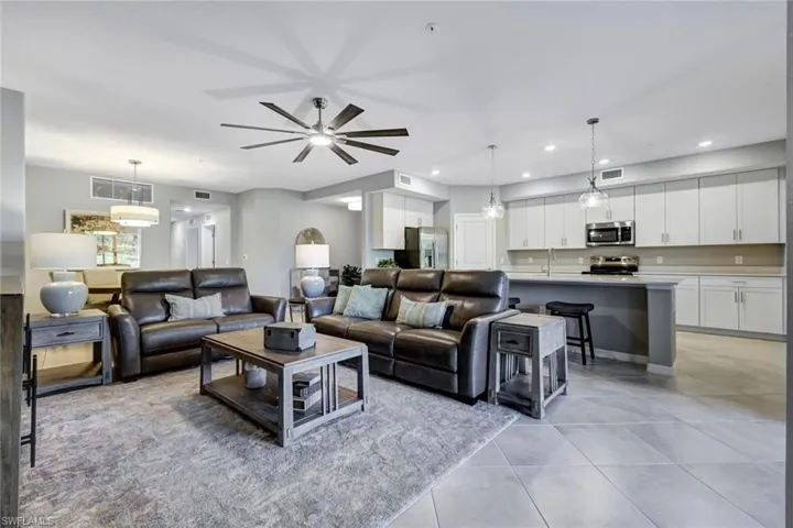 Open floor plan featuring large-format tile flooring, recessed lighting, white shaker-style cabinetry, and a ceiling fan with integrated lighting