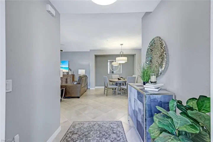 Neutral-tone interior featuring large-format ceramic tile flooring, recessed lighting, and a multi-tiered drum chandelier