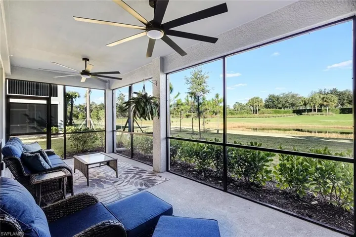 Screened-in lanai featuring dual ceiling fans, concrete flooring, and full-height screens overlooking a manicured GOLF COURSE, lawn and pond