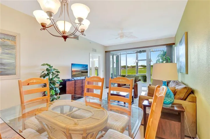Dining room with wood-type flooring and ceiling fan with notable chandelier