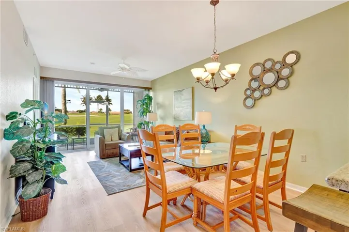 Dining area with wood-type flooring and ceiling fan with notable chandelier