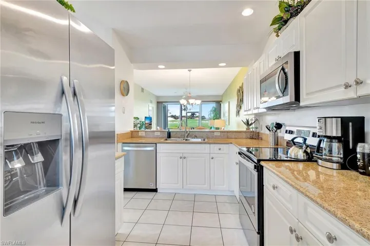 Kitchen featuring a chandelier, stainless steel appliances, white cabinets, sink, and light tile floors