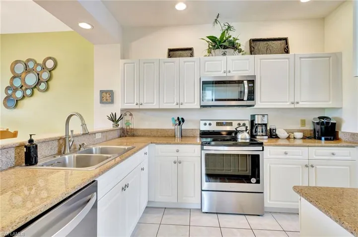 Kitchen featuring white cabinetry, sink, light tile flooring, and stainless steel appliances