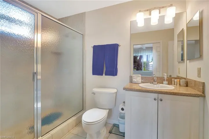 Bathroom featuring tile floors, walk in shower, toilet, and vanity with extensive cabinet space