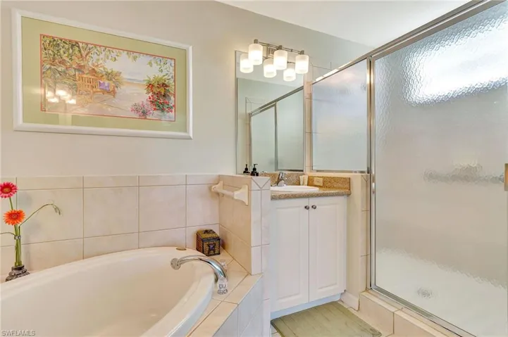 Bathroom with tile floors, vanity with extensive cabinet space, and plus walk in shower