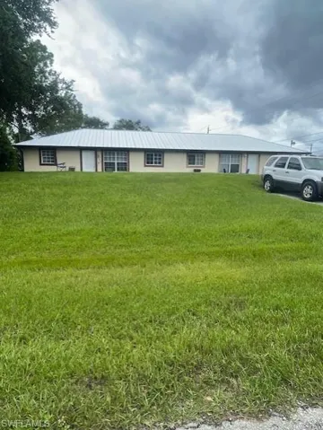 Ranch-style home featuring stucco siding, and newer metal roof, and a front lawn