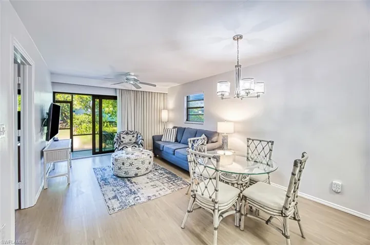 Dining room with wood finished floors, ceiling fan, a chandelier, and baseboards