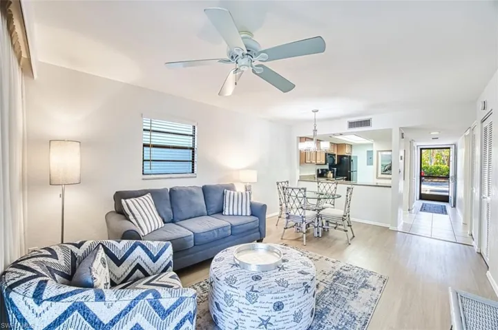 Living area with light wood-style floors, a chandelier, a ceiling fan, and baseboards