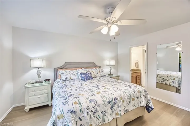 Bedroom featuring light wood-style flooring, baseboards, a ceiling fan, and ensuite bathroom