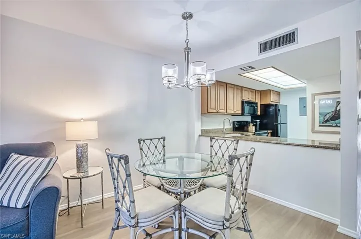 Dining area featuring light wood-type flooring, a chandelier, baseboards, and electric panel