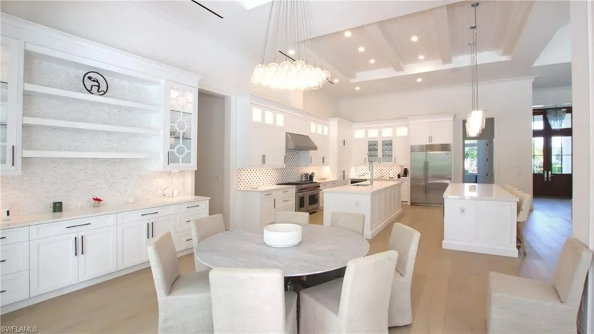 Dining area with a raised ceiling, sink, a notable chandelier, and light wood-type flooring