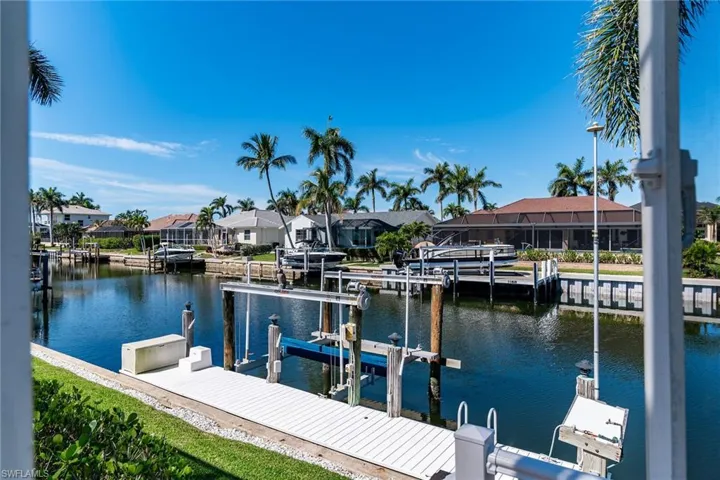 Dock area featuring a water view, boat lift, and a residential view