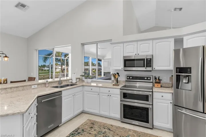 Kitchen with visible vents, white cabinets, lofted ceiling, appliances with stainless steel finishes, and a sink