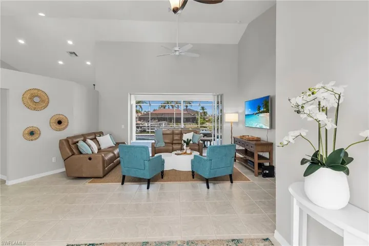 Living area featuring light tile patterned floors, baseboards, visible vents, a ceiling fan, and high vaulted ceiling