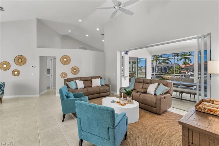 Living room with light tile patterned floors, recessed lighting, visible vents, ceiling fan, and high vaulted ceiling
