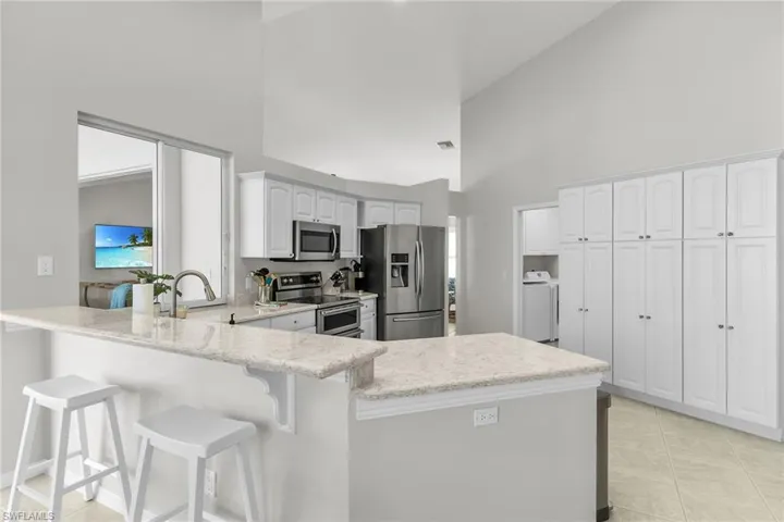 Kitchen featuring stainless steel appliances, a peninsula, a kitchen breakfast bar, and light stone countertops