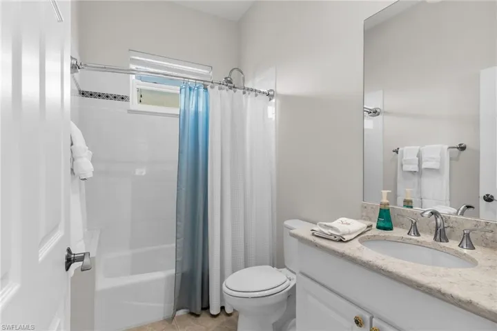 Bathroom with tile patterned flooring, vanity, toilet, and shower / tub combo with curtain