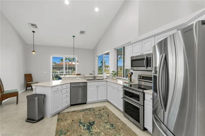 Kitchen featuring visible vents, white cabinets, a peninsula, stainless steel appliances, and a sink