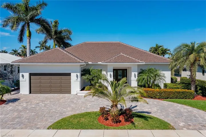 View of front facade with decorative driveway, a tiled roof, an attached garage, and stucco siding