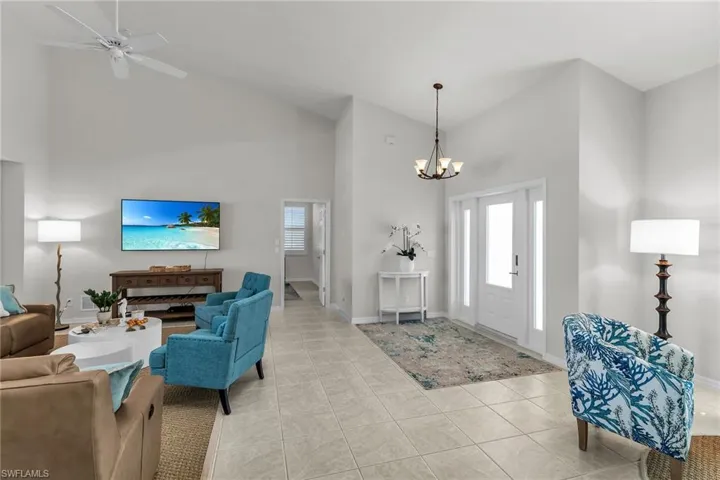 Foyer with light tile patterned floors, baseboards, high vaulted ceiling, and a wealth of natural light